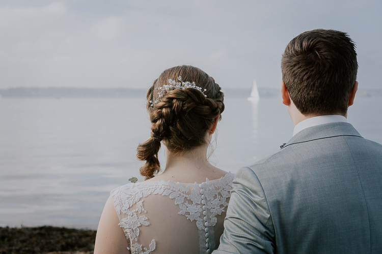 Brautpaar sieht aufs Meer mit Boot